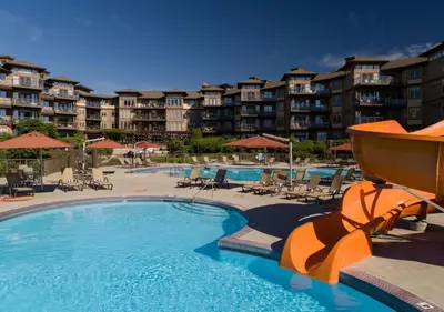 a swimming pool with chairs and umbrellas in a resort at The Cove Lakeside Resort in West Kelowna