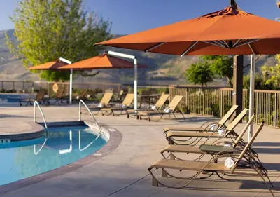 a group of chairs and an umbrella next to a pool at The Cove Lakeside Resort in West Kelowna