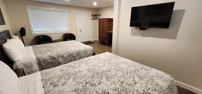 a hotel room with two beds and a flat screen tv at Meares Vista Inn in Tofino