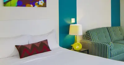 a bedroom with a bed and a chair and a pillow at Hotel Zed Kelowna in Kelowna
