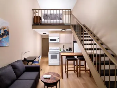 a living room with a couch and a kitchen at Huntingdon Hotel and Suites in Victoria