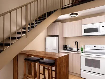 a kitchen with a wooden table and a staircase at Huntingdon Hotel and Suites in Victoria