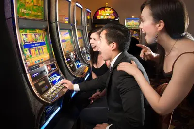 a group of people playing slot machines in a casino at Deerfoot Inn and Casino in Calgary