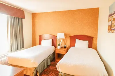 a hotel room with two beds and a window at Service Plus Inns and Suites Calgary in Calgary