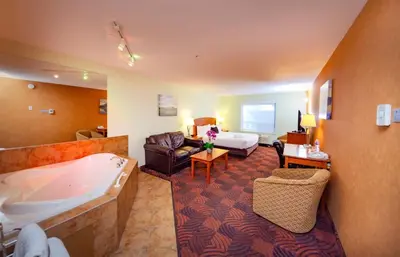 a hotel room with a tub and a bedroom at Service Plus Inns and Suites Calgary in Calgary
