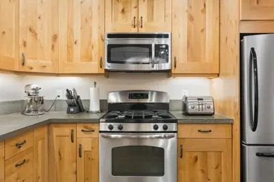 a kitchen with a stainless steel stove and a microwave at The Mountain Project #2 in Rossland