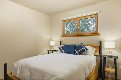 a bedroom with a bed with blue pillows and a window at The Mountain Project #2 in Rossland