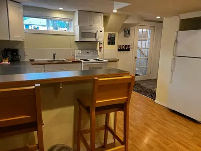 a kitchen with white cabinets and a counter with stools at Revelstoke Long Term in Revelstoke