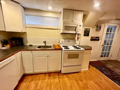 a kitchen with white cabinets and a stove and a sink at Revelstoke Long Term in Revelstoke