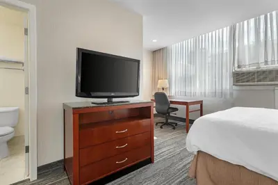 a hotel room with a bed and a television on a dresser at Best Western Plus Suites Downtown Calgary in Calgary