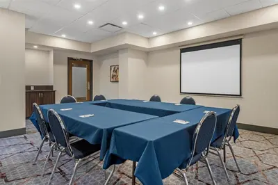 a conference room with a table and chairs and a screen at Best Western Plus Suites Downtown Calgary in Calgary