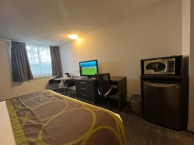 a hotel room with a bed and a desk with a computer at Super 8 by Wyndham Macleod Trail Calgary in Calgary