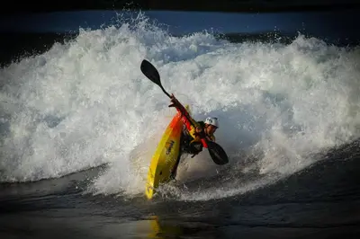 a man riding a wave on a kayak in the ocean at The Perch at Moon Dance in Garden Bay