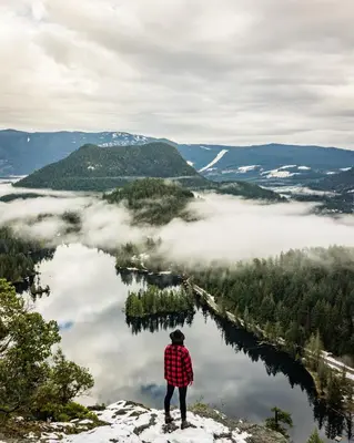a person standing on top of a mountain looking at a lake at The Perch at Moon Dance in Garden Bay