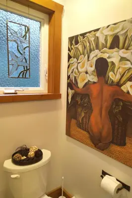 a painting of a man sitting on a toilet in a bathroom at The Cabin at Moon Dance in Garden Bay