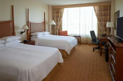 a hotel room with two beds and a desk and a television at River Cree Resort & Casino in Edmonton
