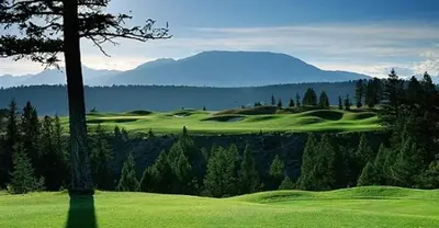 a view of a golf course with mountains in the background at Mountain View Radium Condo - Copper Horn Village in Radium Hot Springs