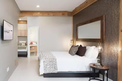 a bedroom with a white bed and a mirror on the wall at The Rockwell-Harrison Guest Lodge in Harrison Hot Springs