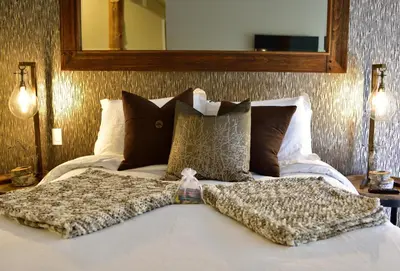 a bed with a blanket on top of it at The Rockwell-Harrison Guest Lodge in Harrison Hot Springs