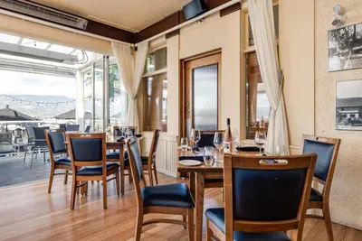 a restaurant with wooden tables and chairs and a large window at Hotel Eldorado at Eldorado Resort in Kelowna