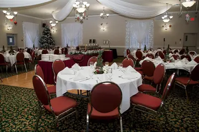 a banquet hall with white tables and chairs and a christmas tree at Days Inn by Wyndham Penticton Conference Centre in Penticton