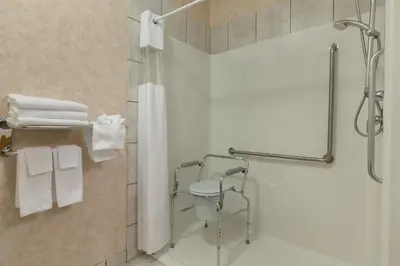 a bathroom with a shower and a toilet and towels at Days Inn by Wyndham Penticton Conference Centre in Penticton