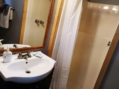 a bathroom with a sink and a shower with a mirror at Overlook Inn & Cabins in Clearwater