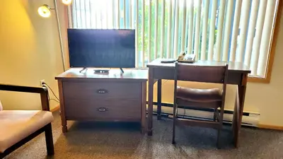 a desk with a chair and a dresser with a television at Sea Raven Motel in Queen Charlotte