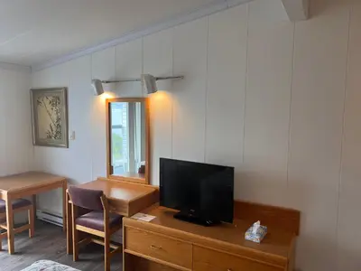 a living room with a tv and a desk with a chair at Sea Raven Motel in Queen Charlotte