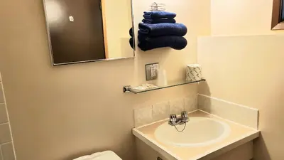 a bathroom with a sink and a mirror and blue towels at Sea Raven Motel in Queen Charlotte