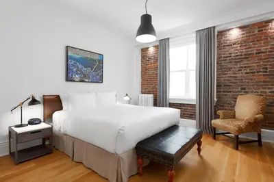 a bedroom with a bed and a brick wall at Victorian Hotel in Vancouver