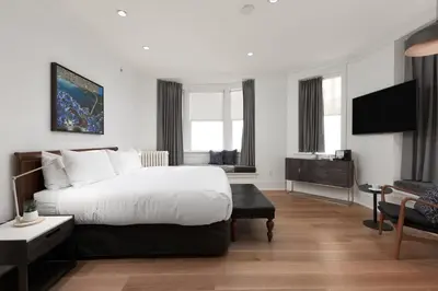 a hotel room with a bed and a tv at Victorian Hotel in Vancouver