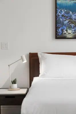 a bedroom with a bed and a desk with a lamp at Victorian Hotel in Vancouver