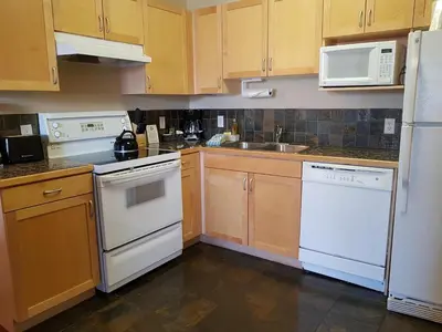 a kitchen with white appliances and wooden cabinets at Sunset Resorts Canmore and Spa in Canmore