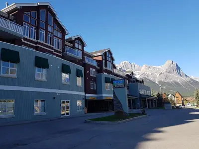 a large building with a mountain in the background at Sunset Mountain Inn in Canmore
