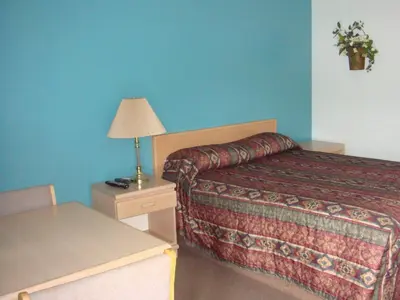 a bedroom with a bed and a table with a lamp at Trans Canada Motel in Kamloops