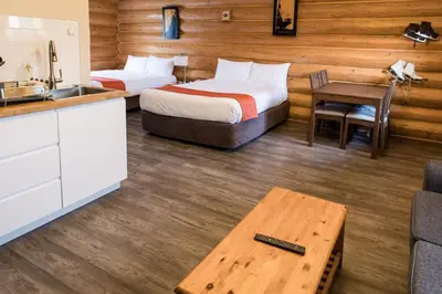 a hotel room with two beds and a table at Glacier House Hotel & Resort in Revelstoke