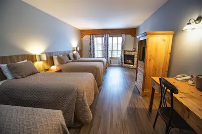 a hotel room with three beds and a television at Glacier House Hotel & Resort in Revelstoke