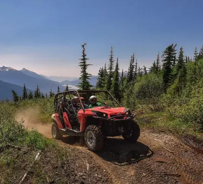a person riding a red atv on a dirt road at Glacier House Hotel & Resort in Revelstoke