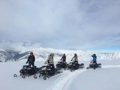 a group of people on a snowmobile in the snow at Glacier House Hotel & Resort in Revelstoke