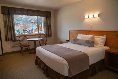 a hotel room with a bed and a table and a window at Rocky Mountain Ski Lodge in Canmore