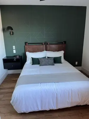 a bedroom with a large white bed with a green wall at Baymont by Wyndham Fort McMurray in Fort McMurray