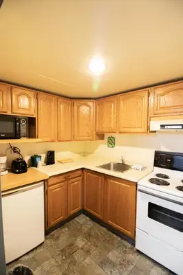a kitchen with wooden cabinets and white appliances at Divya Sutra Plaza and Conference Centre, Vernon, BC in Vernon