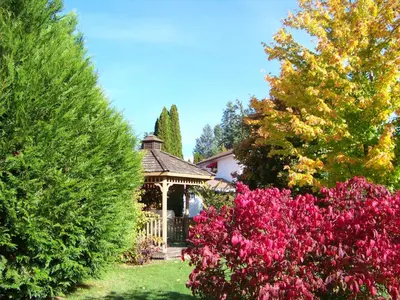 a gazebo in a garden with trees and flowers at Bavarian Orchard Motel in Creston