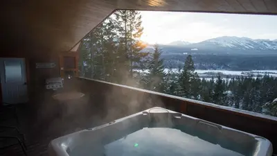 a bath tub in a room with a large window at Cedar House Restaurant & Chalets in Golden