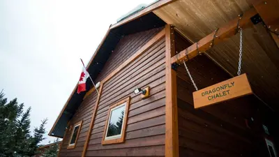 a wooden building with a sign on the side of it at Cedar House Restaurant & Chalets in Golden