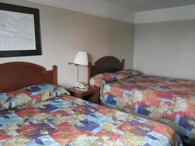 a hotel room with two beds and a phone on a table at Moby Dick Inn in Prince Rupert