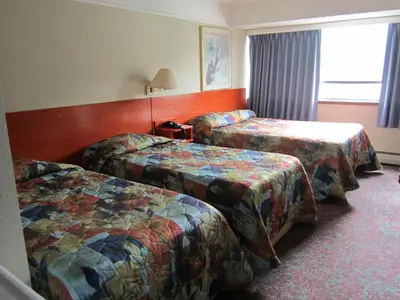 a hotel room with three beds and a window at Moby Dick Inn in Prince Rupert