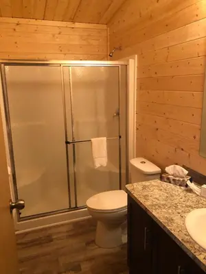 a bathroom with a shower with a toilet and a sink at Camperland RV Resort & Cabins in Rosedale