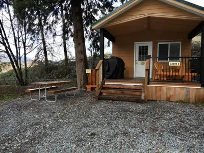 a cabin with a bench and a table in front of it at Camperland RV Resort & Cabins in Rosedale